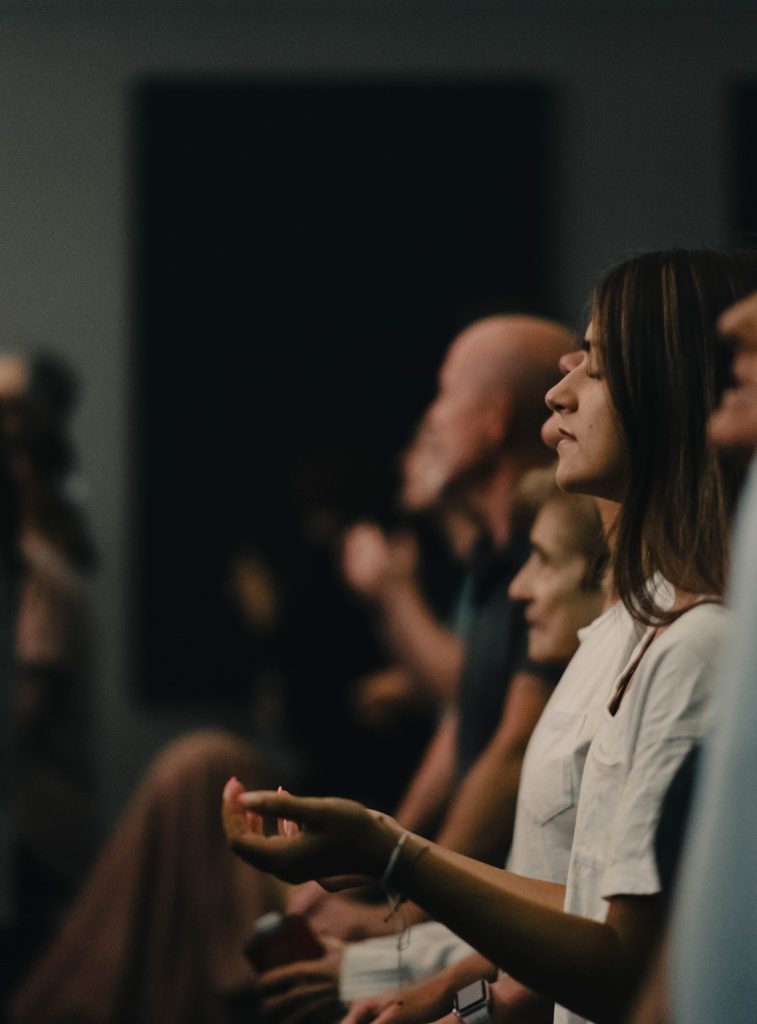 Young adult with hands raised in worship at Church of the Valley in Chicopee, Pioneer Valley MA