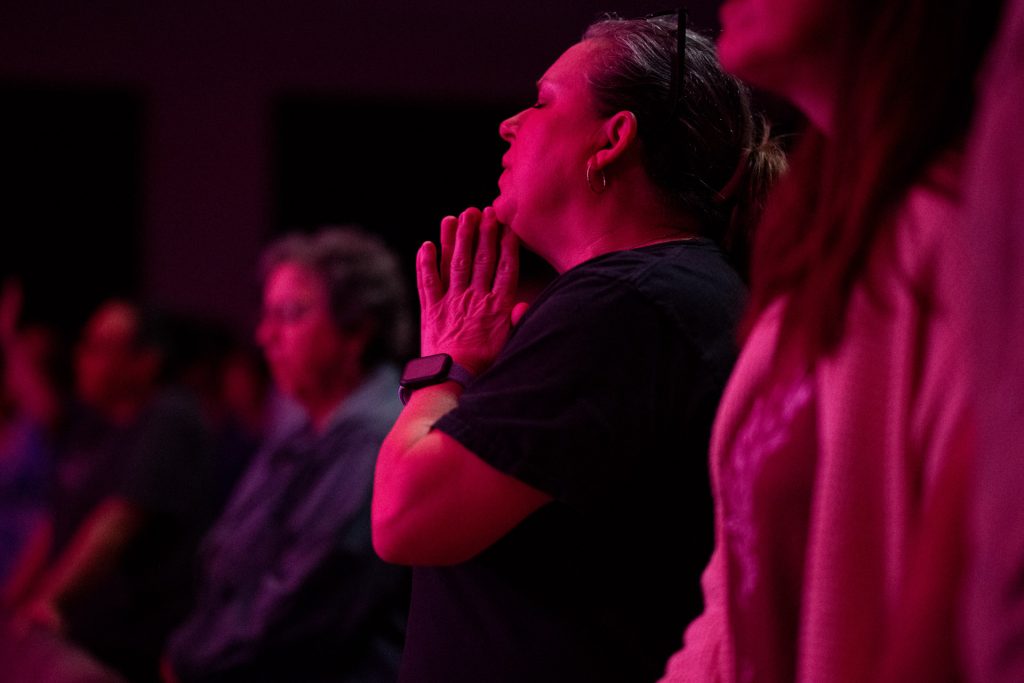 Woman in pink lights in worship at Church of the Valley in Chicopee, Pioneer Valley MA