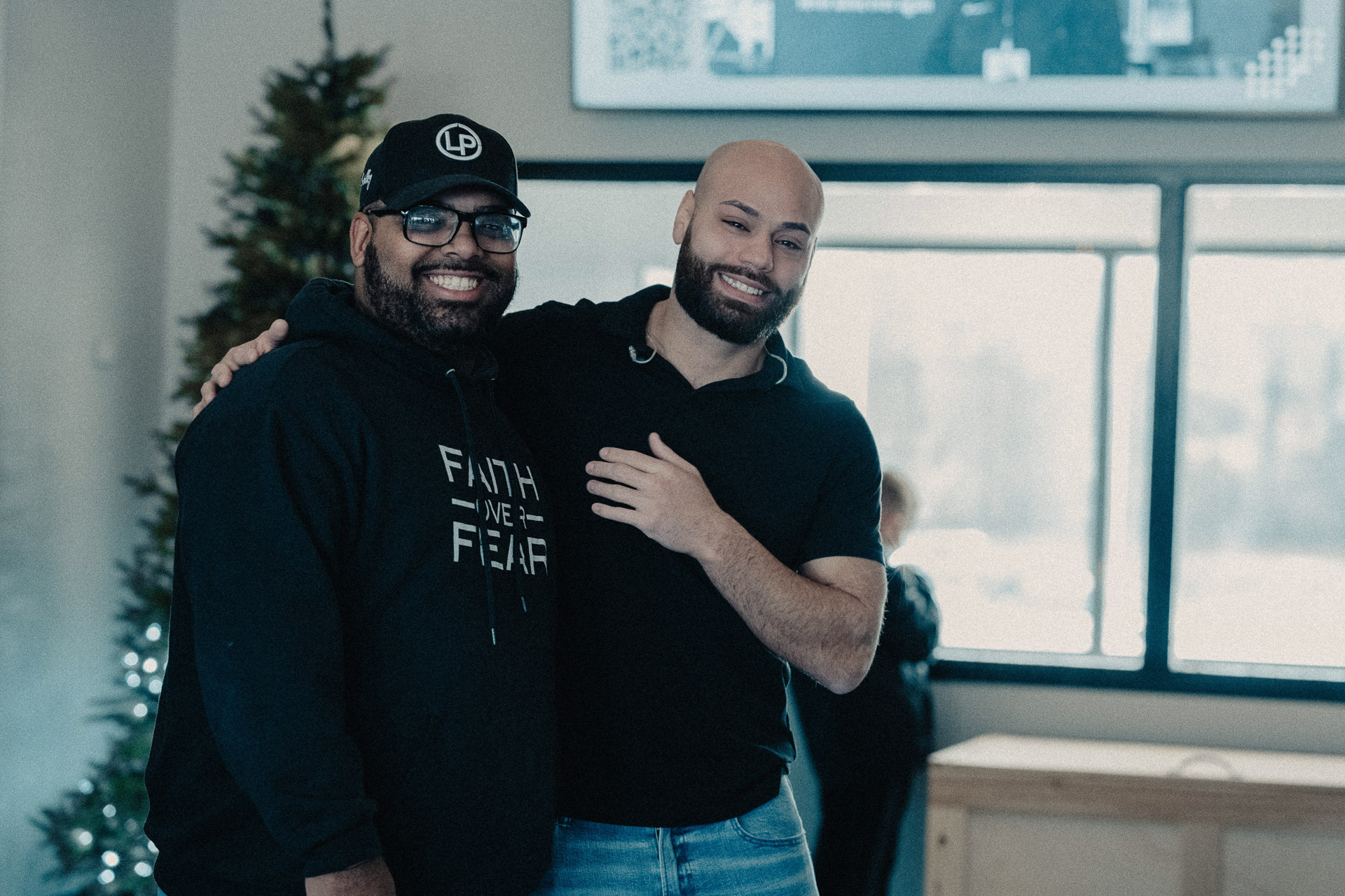 Two men hugging in front of a tree at Church of the Valley in Chicopee, Pioneer Valley MA.